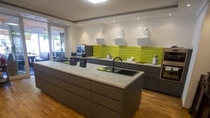 Uma cozinha moderna com uma ilha grande, eletrodomésticos embutidos e um painel de parede verde vibrante.