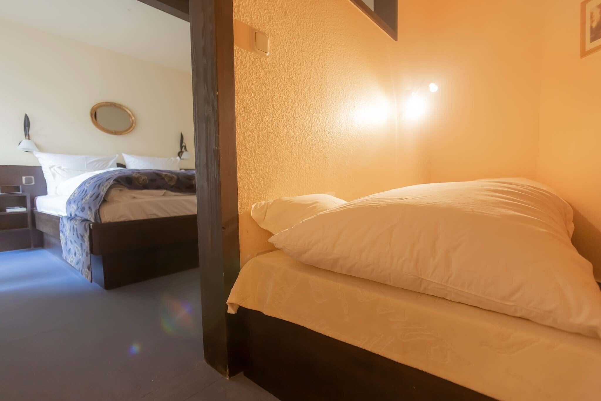 A hotel room with a bed, a bedside table, and a mirror on the wall.
