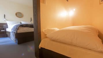 A hotel room with a bed, a bedside table, and a mirror on the wall.