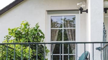 A balcony with a chair, a window, and a wall covered in ivy.