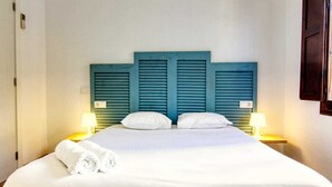 Ein ordentlich bezogenes Bett mit weißen Leinen und zwei Kissen, begleitet von zwei Nachttischlampen auf passenden Nachttischen.