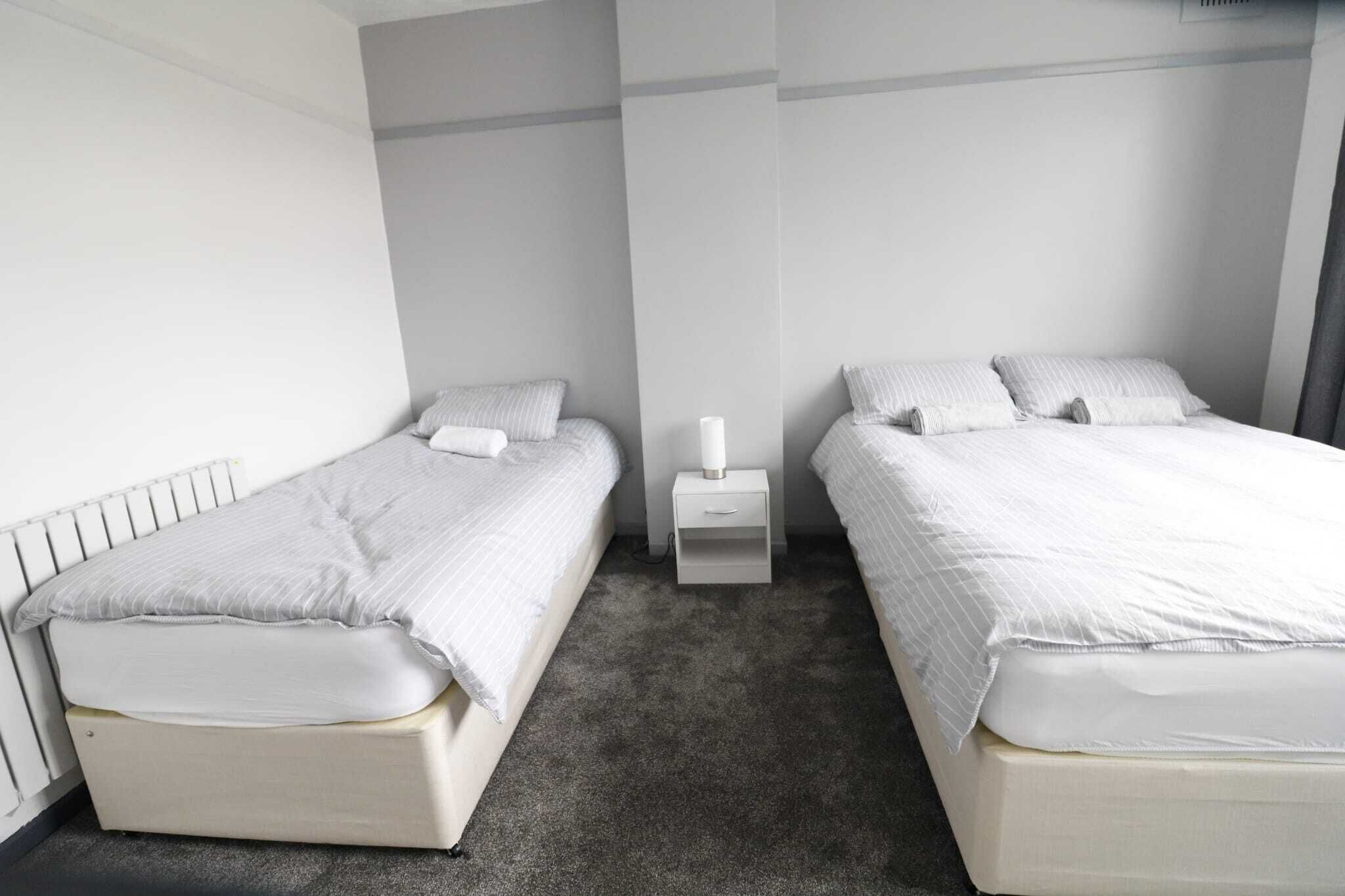 A twin room with two beds, a small bedside table, and a radiator.