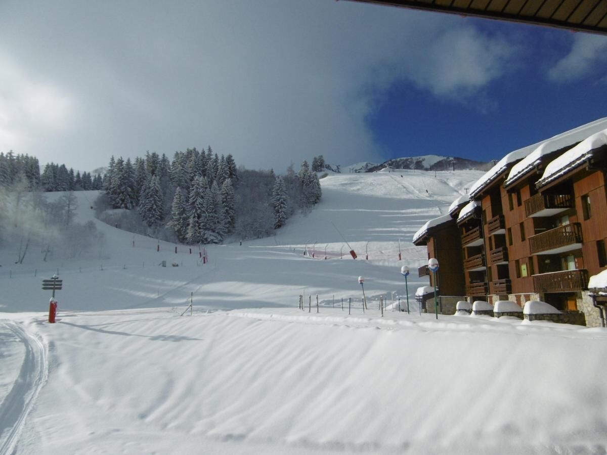 A snow-covered ski slope with a building on the right.