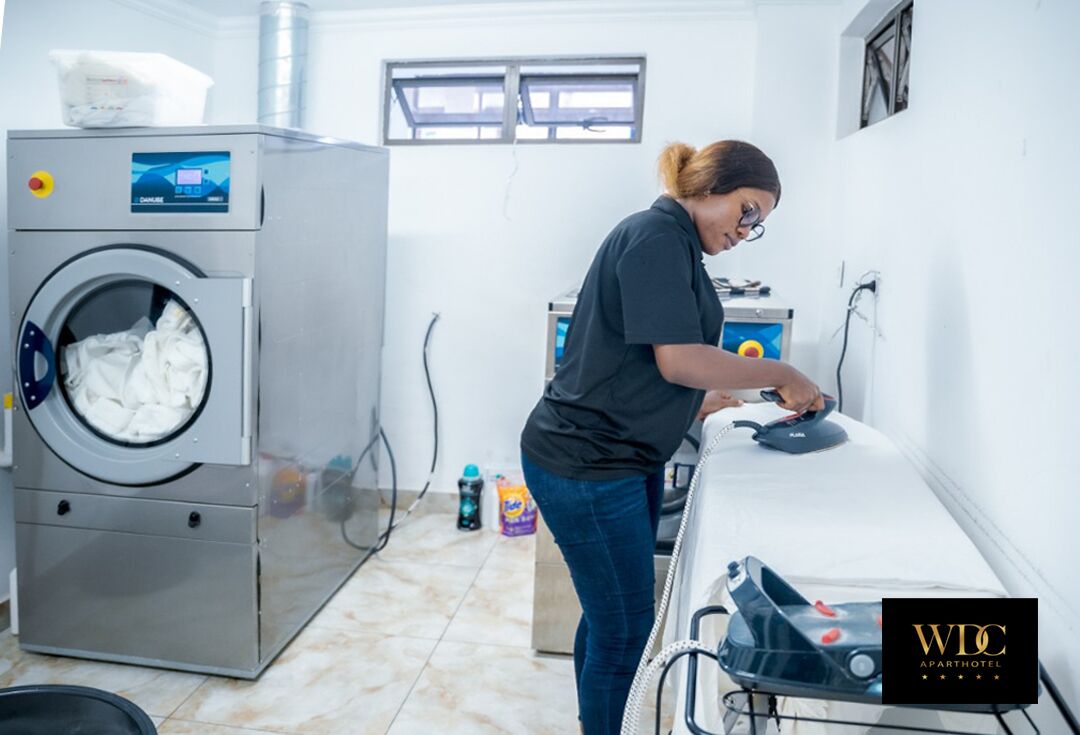 Un espace buanderie équipé d’un lave-linge et d’une planche à repasser.