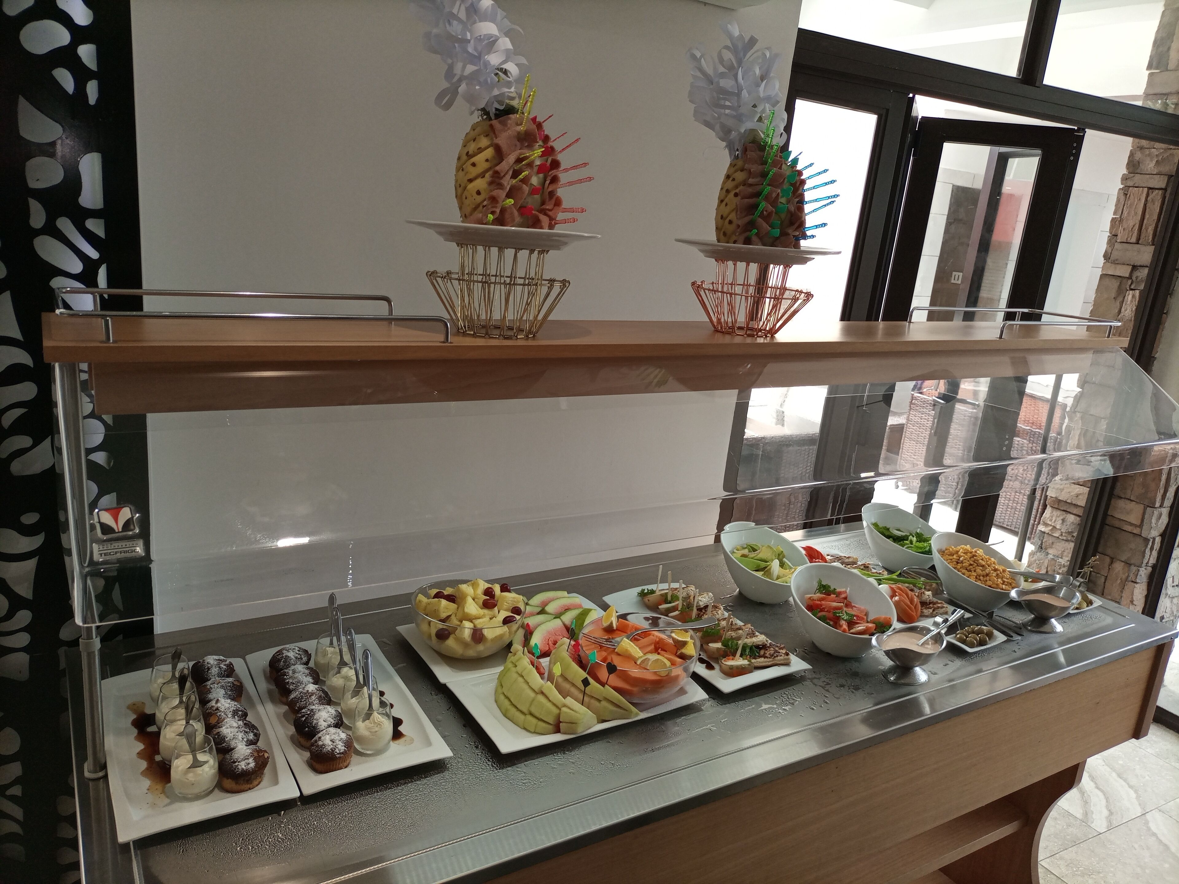A buffet with various food items including pastries, fruits, and salads.