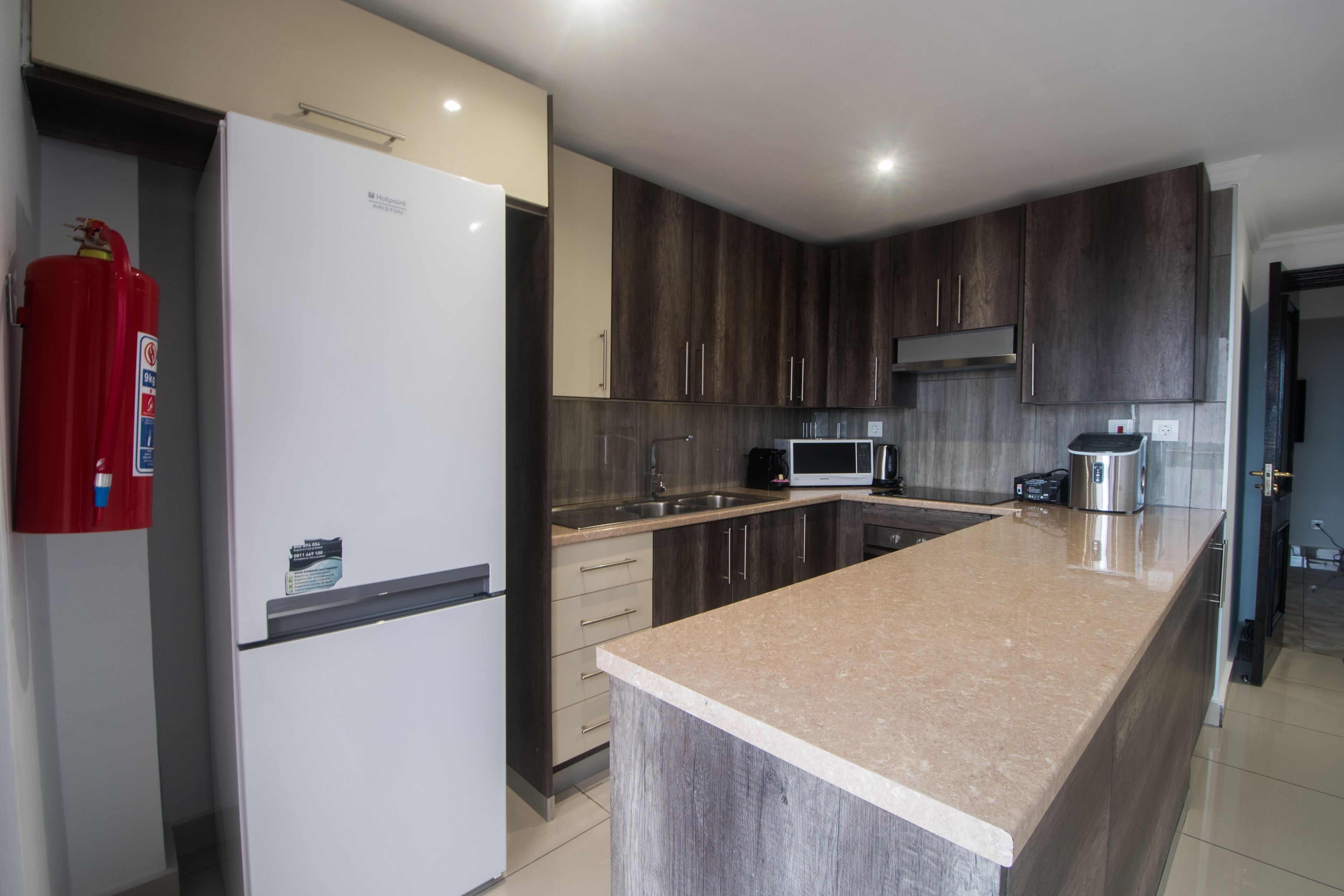 A modern kitchen with a large island, stainless steel appliances, and dark wood cabinets.