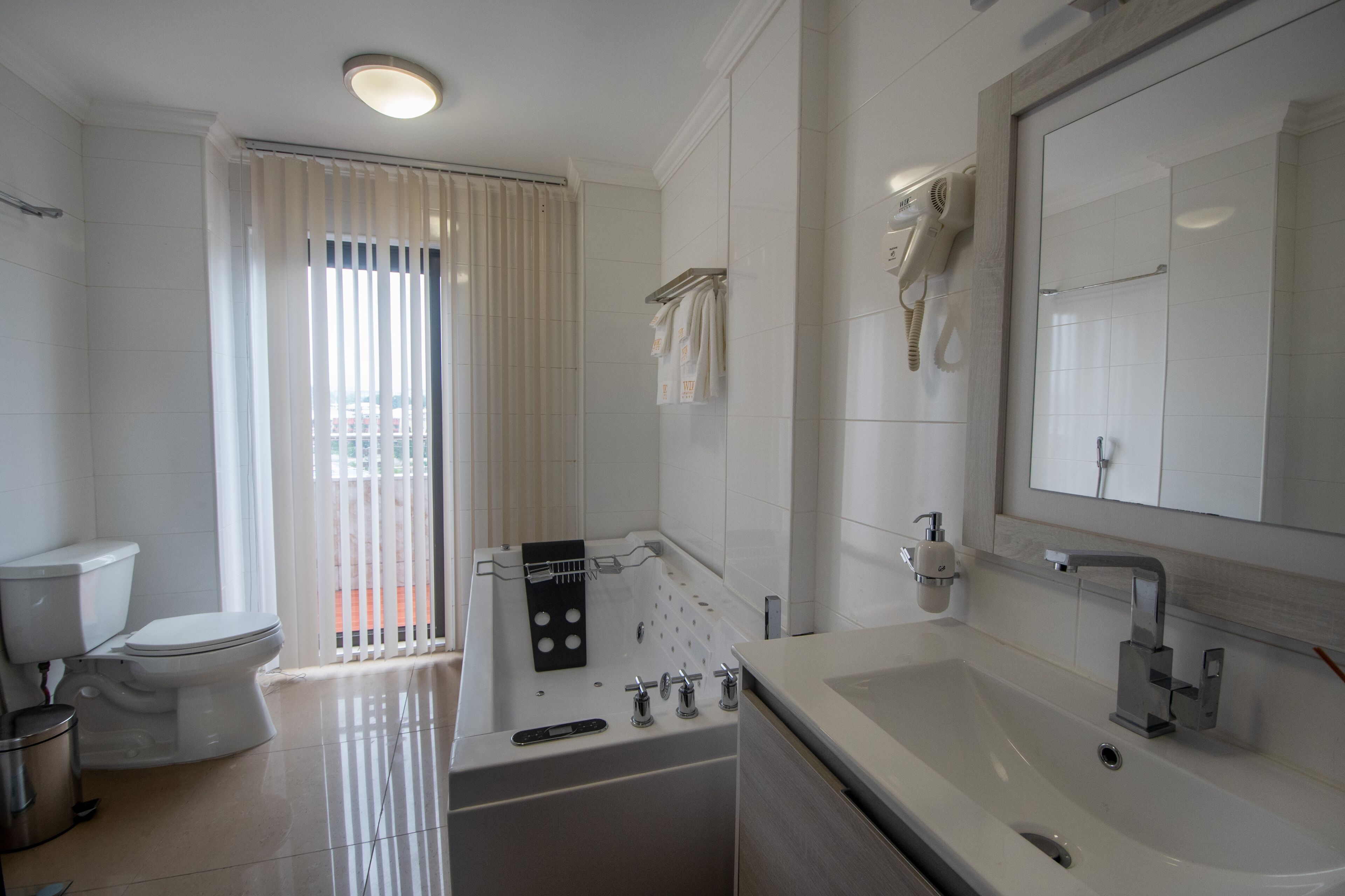 A modern bathroom with a bathtub, a large mirror, and a toilet.