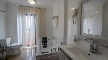 Un baño moderno con una bañera, un espejo grande y un inodoro.