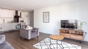 A modern living room with a grey sofa, a coffee table, and a TV on a wooden stand. - Stay Zeni, Ouse Court York Contemporary 2 Bed Flat (York)