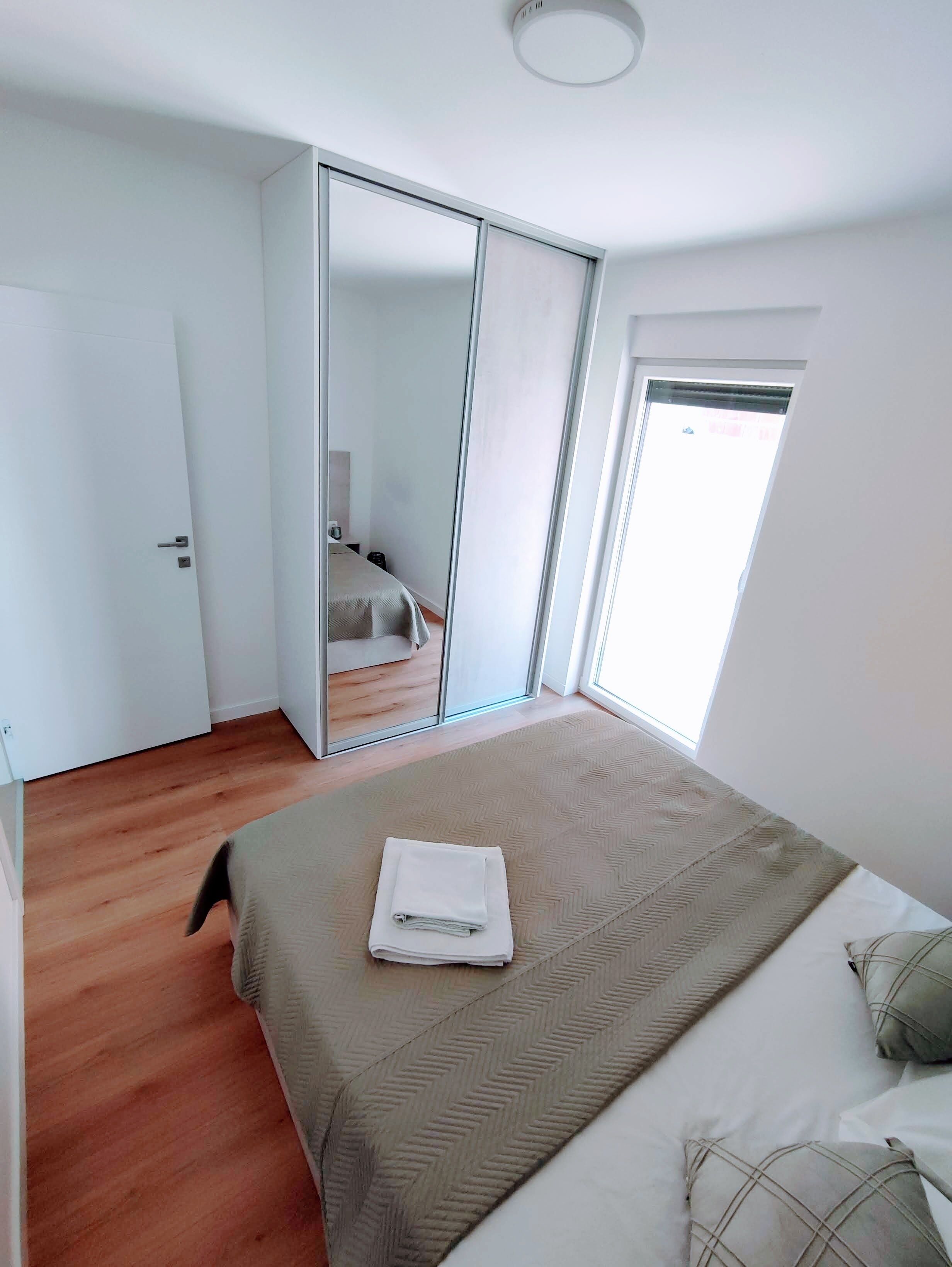 Un dormitorio con cama, armario y ventana.