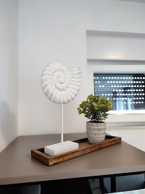 A white spiral sculpture on a white base, a potted plant, and a wooden tray on a table. - Brand new 3-bed Apartment (Pag)