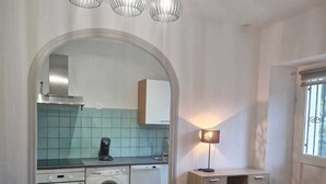 A modern kitchen with a washing machine, oven, and a dining area with a table and chairs.