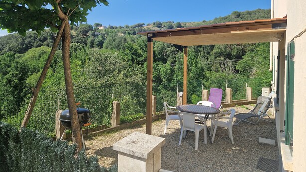 A patio with a table and chairs, a barbecue grill, and a pergola.