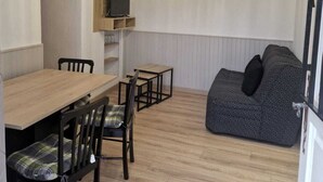 A compact living space with a dining area, a sofa, and a TV mounted on the wall.