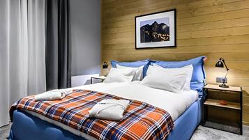 A hotel room with a bed, a nightstand, a lamp, a framed picture on the wall, and a window with curtains.
