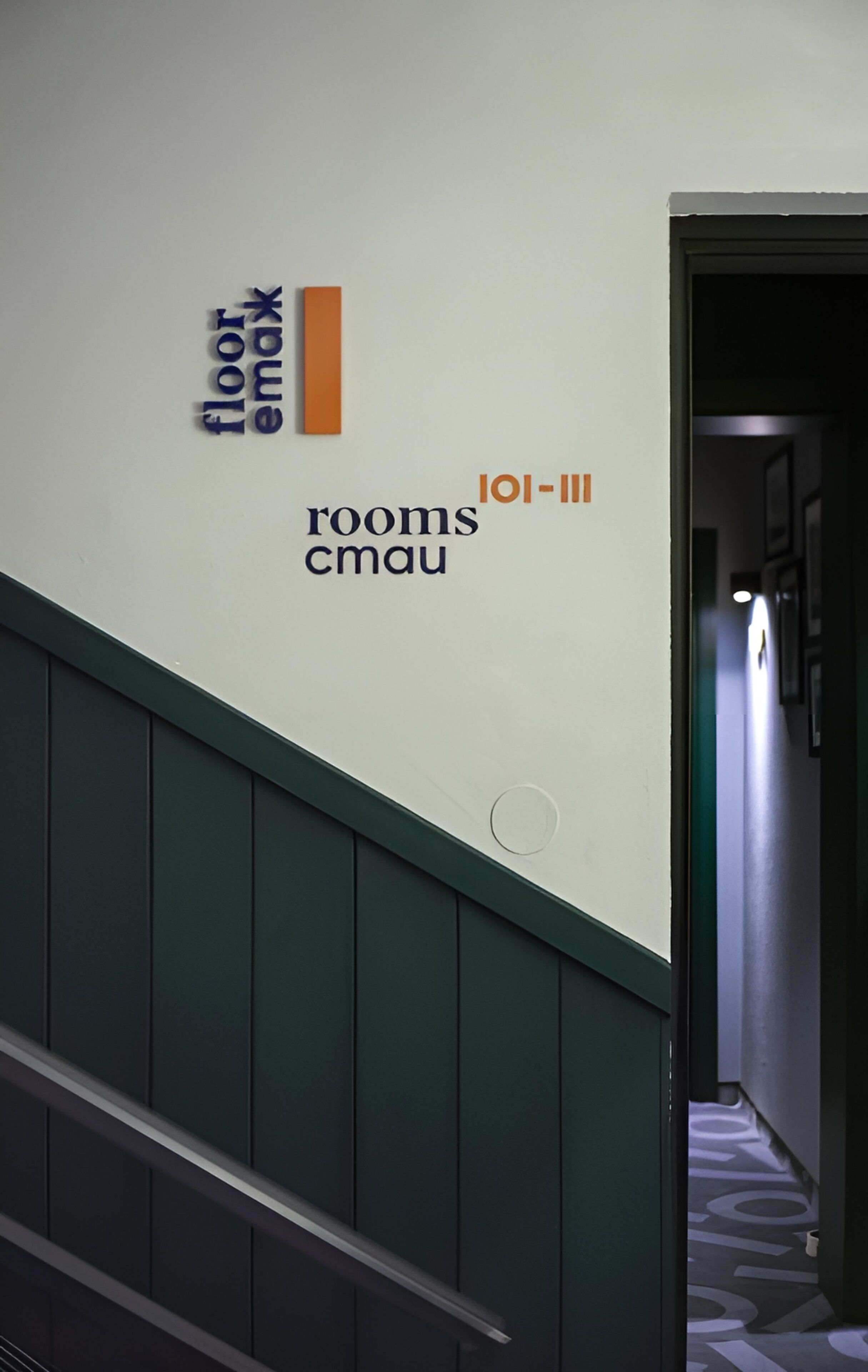 A hallway with a staircase, a wall with text indicating 'floor max', 'rooms cmau', and 'loi-iii'.