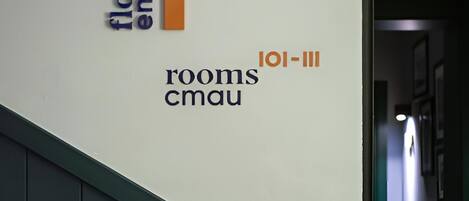 A hallway with a staircase, a wall with text indicating 'floor max', 'rooms cmau', and 'loi-iii'.