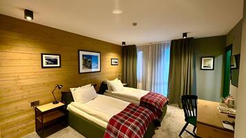 Una habitación de hotel con dos camas, un escritorio, una silla y una mesita.