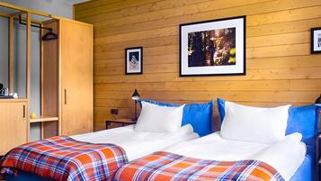 A bedroom with a wooden wall, a bed with white and blue pillows, and a plaid blanket.