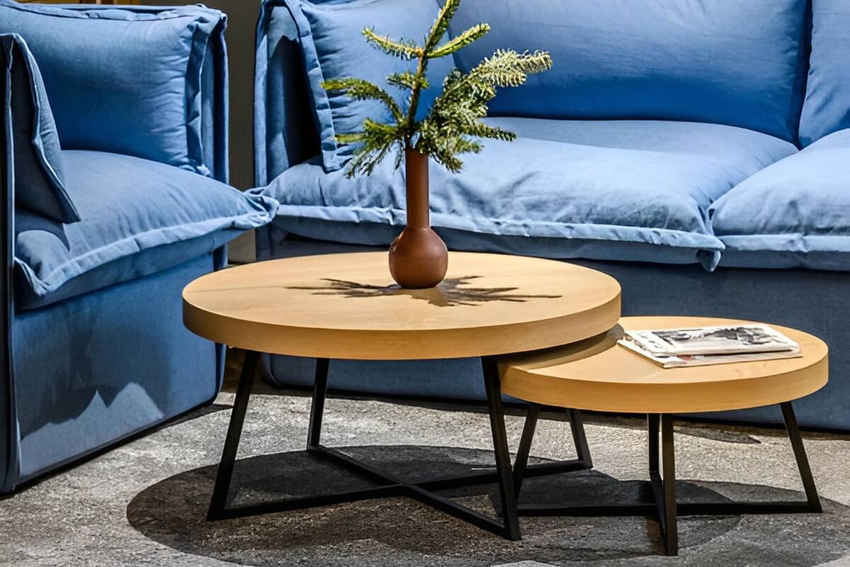 A modern living room with a blue sofa, a round wooden coffee table, and a floor lamp.