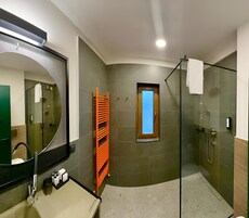 Un baño moderno con ducha de vidrio, un espejo grande y un perchero para toallas.
