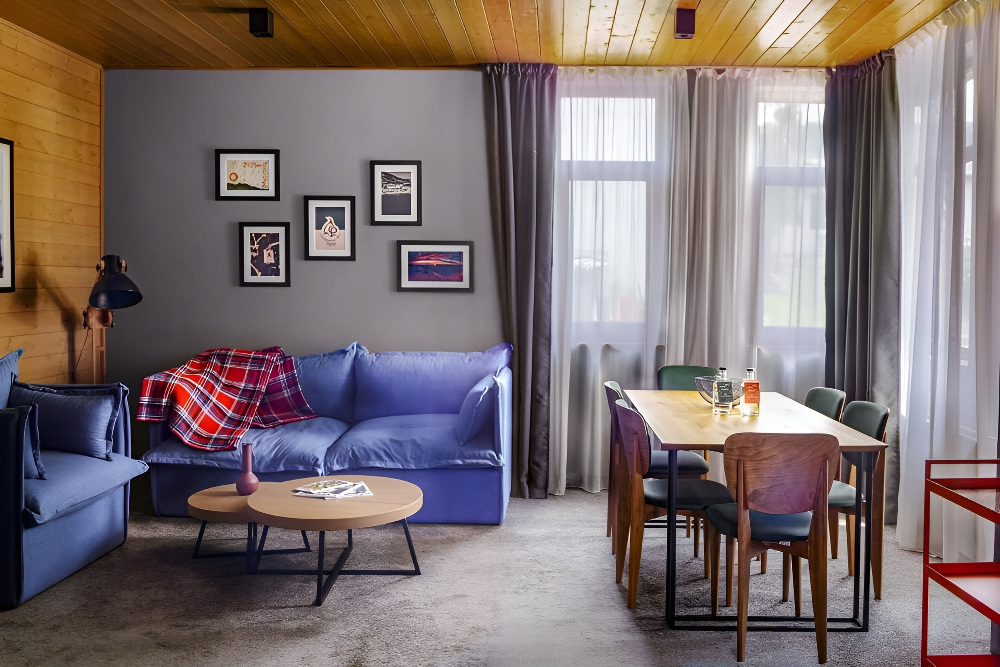 Un soggiorno moderno con un divano blu, un tavolino rotondo e un'area pranzo con un tavolo in legno e sedie.