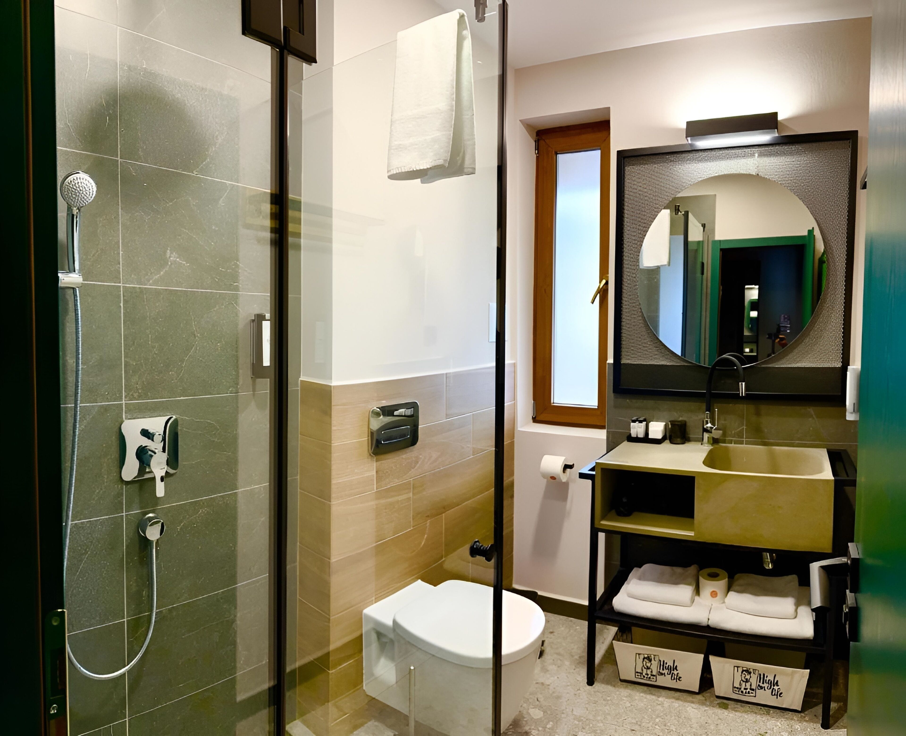 Un baño moderno con ducha de vidrio, inodoro, lavabo con espejo y un perchero para toallas.