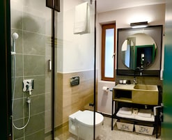 Un baño moderno con ducha de vidrio, inodoro, lavabo con espejo y un perchero para toallas.