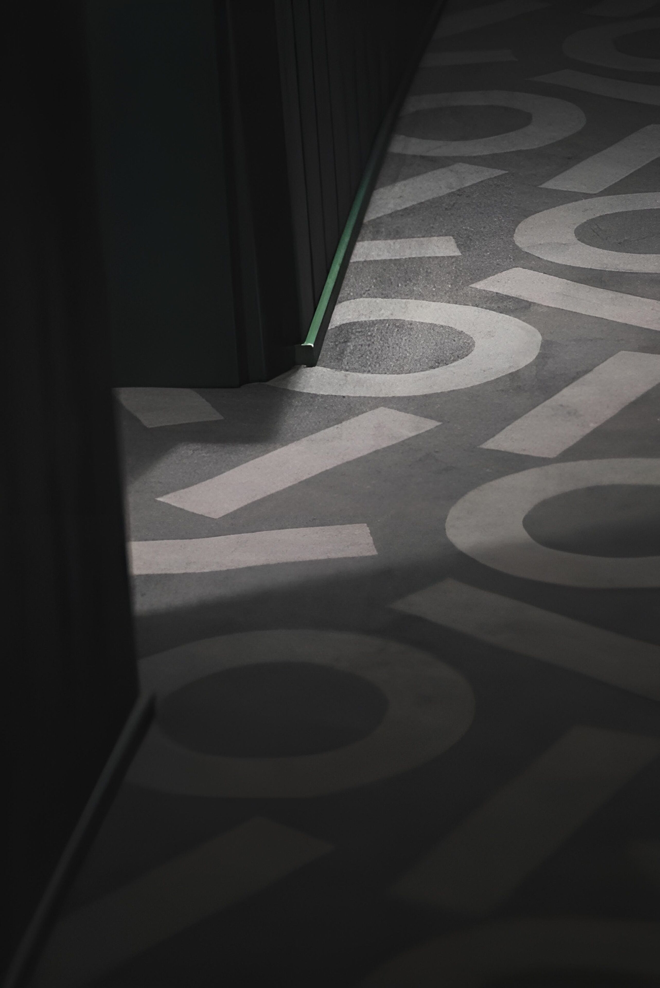 Un couloir doté d’un sol à motifs et d’une ligne verte indiquant un chemin.