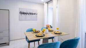 A dining area with a wooden table, blue chairs, and breakfast items including croissants and orange juice.