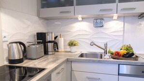 A modern kitchen with a built-in stove, stainless steel appliances, and a fruit bowl on the counter.