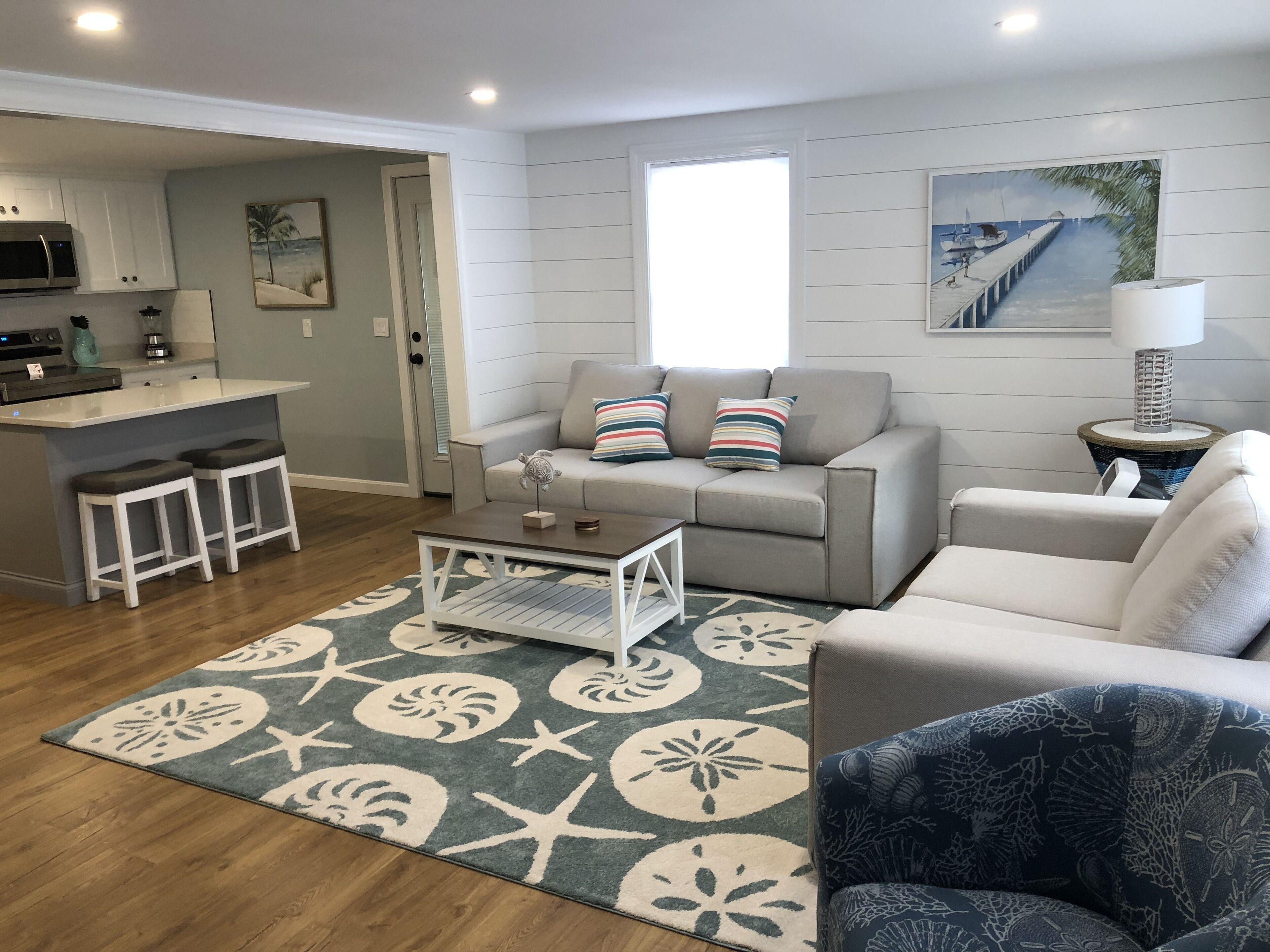 A modern living room with a grey sofa, a coffee table, and a patterned rug.
