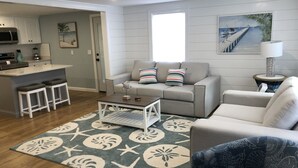 A modern living room with a grey sofa, a coffee table, and a patterned rug. - Beautiful 4 Bedroom short walk to the Pier, Beach, & Attractions (Old Orchard Beach)