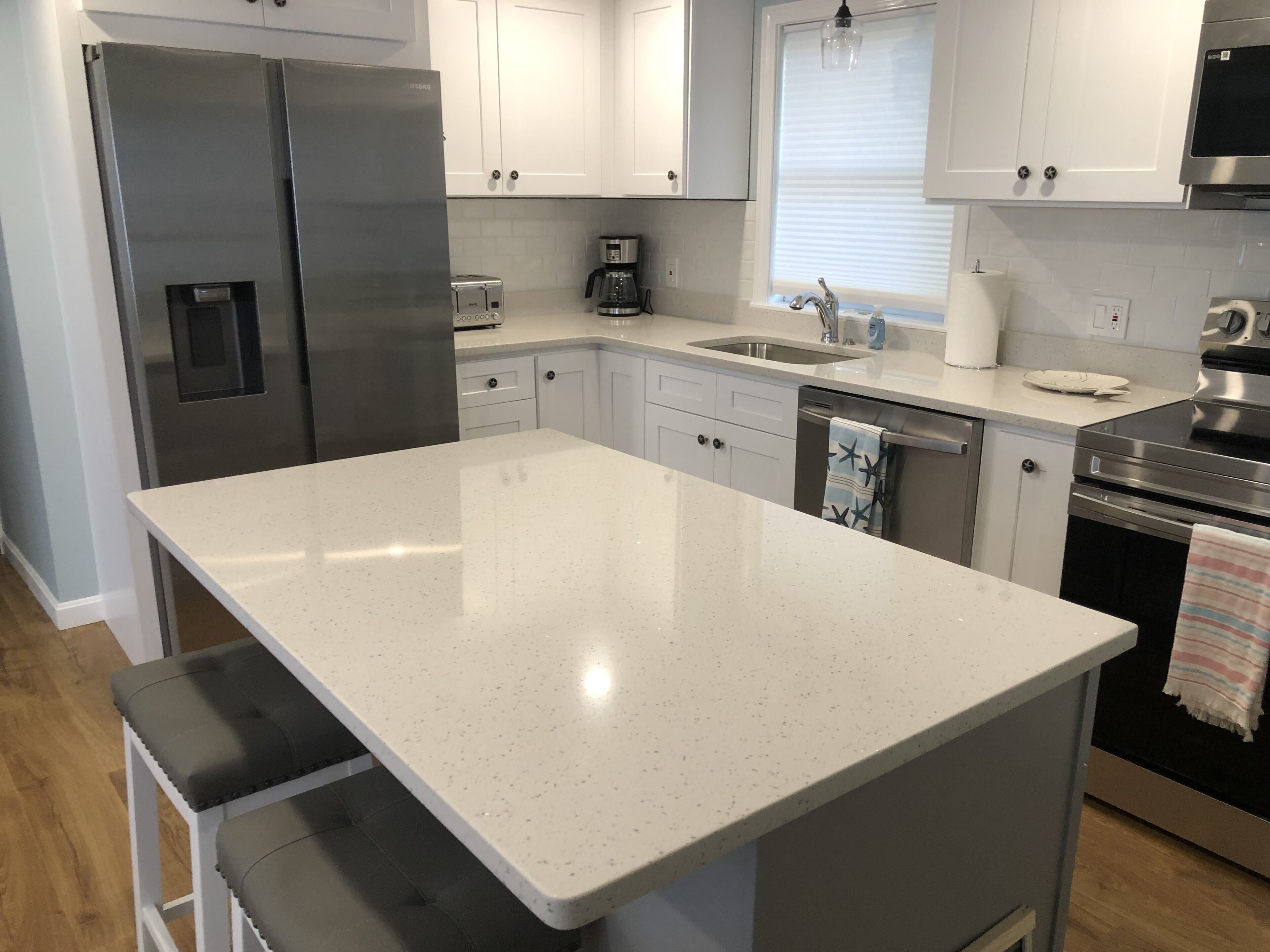 A modern kitchen with white cabinetry, stainless steel appliances, and a central island.