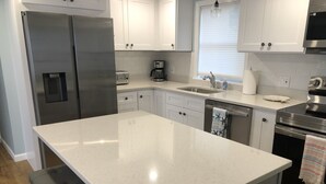 A modern kitchen with white cabinetry, stainless steel appliances, and a central island. - Beautiful 4 Bedroom short walk to the Pier, Beach, & Attractions (Old Orchard Beach)