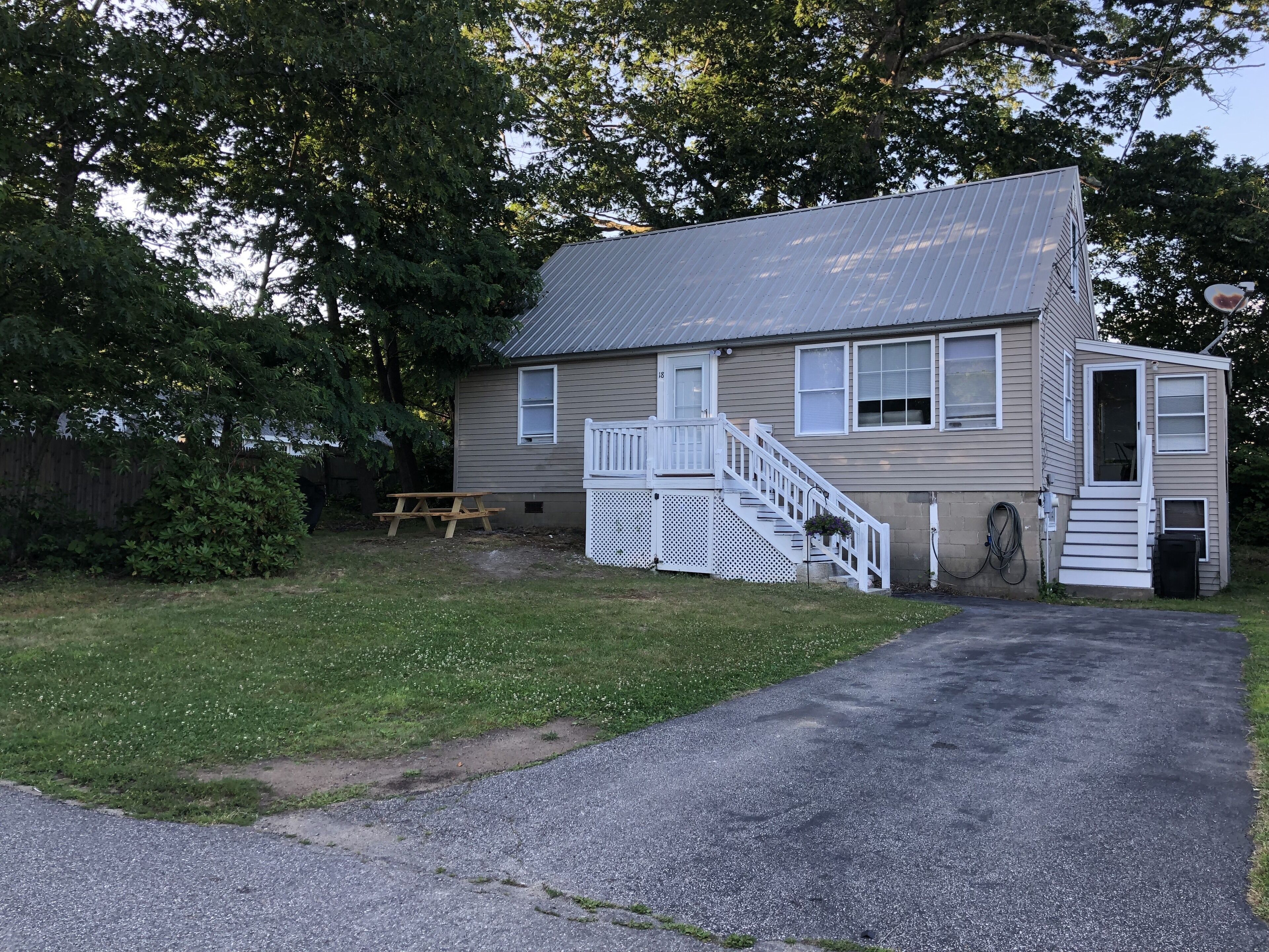 A single-story house with a front porch, a small attached garage, and a picnic table in the yard.
