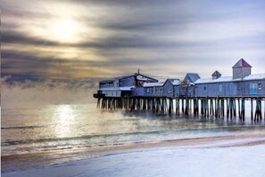 A pier with buildings extending over the water, featuring a prominent structure with a red roof.