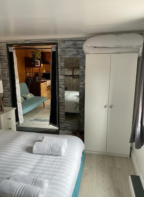 A bedroom with a bed, a wardrobe, and a view into the living area.