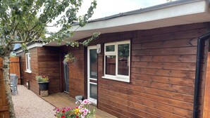 A wooden house with a gravel patio, a door, and a window. - Charming Chalet - Sleep 3/4 & Free Parking (Dartmouth)