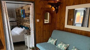 A cozy room with a blue sofa, a small table, and a mirror on the wall. - Charming Chalet - Sleep 3/4 & Free Parking (Dartmouth)