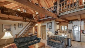 A spacious living area with a wooden staircase, a sofa, a coffee table, and a patterned rug. - Eagles Nest On Smith Lake (Garrison)