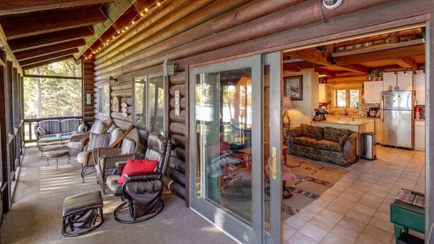 A log cabin with a porch, a living room with a sofa and chairs, and a kitchen area. - Eagles Nest On Smith Lake (Garrison)
