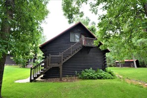 Une cabane en rondins avec un escalier en bois menant à un balcon.