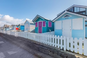 A row of beach huts with white picket fences, each with a distinct color and a garage door. - 2 Bed in Bideford (oc-pd693a) (Northam)