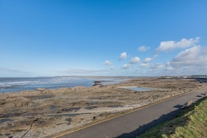 A coastal road with rocky terrain and a clear sky.