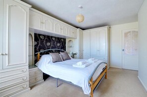 A bedroom with a bed, white wardrobe, and a hanging light fixture.