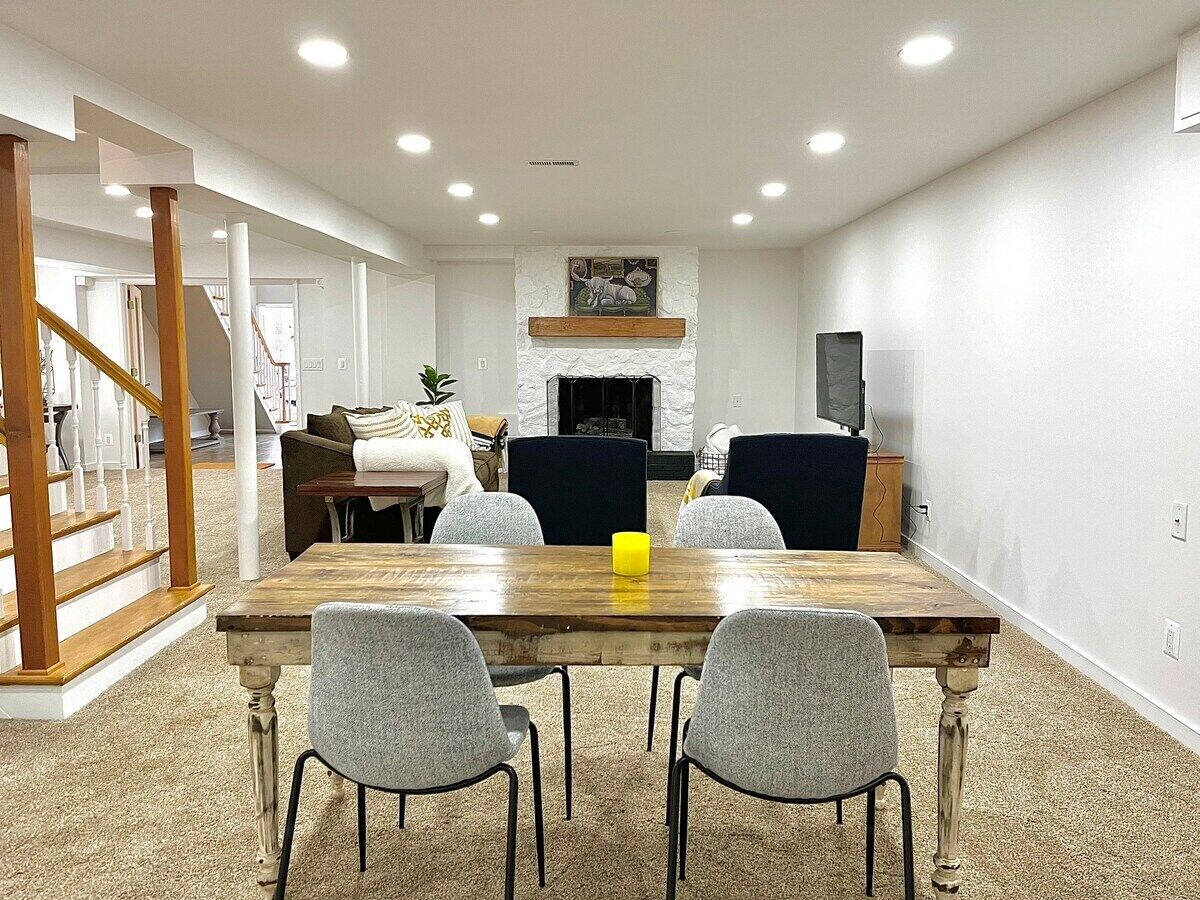 A dining area with a wooden table and four chairs, a fireplace, and a television on the wall.