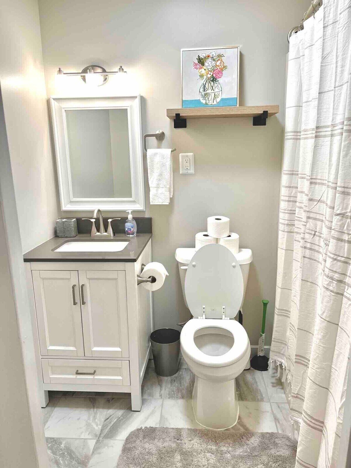 A bathroom with a white sink, mirror, toilet, and a shower curtain.