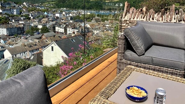 Ein Balkon mit Korbmöbeln, einem Tisch und einer Schüssel Chips.
