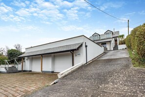 A two-story building with a garage, a staircase, and a paved driveway. - 6 Bed in Woolacombe (oc-mouro) (Woolacombe)